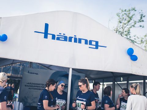 Mitarbeiter stehen unter einem Pavillon, drauf ein weiß/blaues Häring logo 
