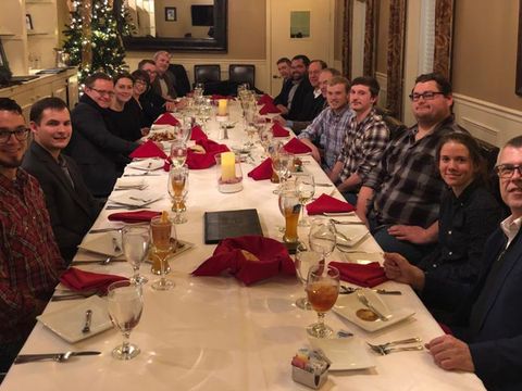 Gruppenfoto Geschäftsleitung Mitarbeiter Häring langen Tisch gedeckt Weihnachtsfeier alle lächelnd in die Kamera