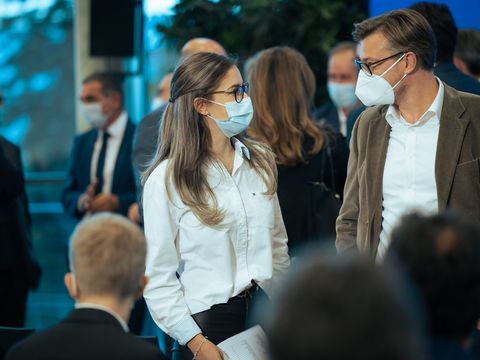 braunhaarige Frau mit Gesichtsmaske unterhaltet sich mit einem braunhaarigen Mann mit Brille und Gesichtsmaske