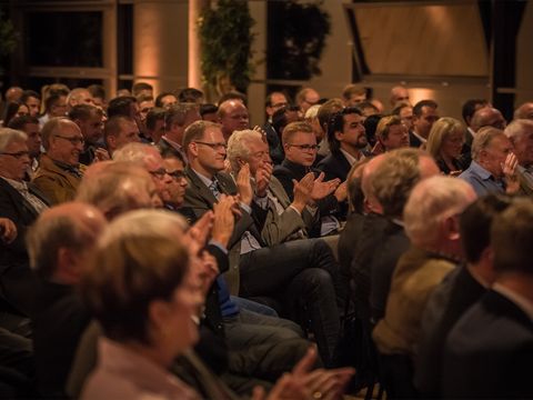 Publikum sitzt in einem Saal und klatscht in die Hände